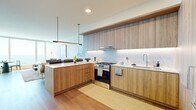 Located along Chicago's iconic Michigan Avenue, this thoughtfully designed one-bedroom, one-bathroom residence offers a refined urban living experience with sweeping views of Lake Michigan and Grant Park. The open-concept layout connects the kitchen and living areas seamlessly, maximizing the sense of space throughout.

The kitchen is a standout feature, showcasing warm wood-toned cabinetry extending floor to ceiling, a marble-inspired backsplash with under-cabinet lighting, stainless steel gas range, and a peninsula with white quartz countertops — ideal for both cooking and casual dining. Light wood flooring flows throughout the space, complementing the contemporary aesthetic.

The living room is anchored by expansive floor-to-ceiling windows that flood the room with natural light and frame breathtaking panoramic views of the lakefront. A dedicated dining nook sits beside the windows, making the most of the scenery.

The bedroom continues the view-forward design, with large windows overlooking Lake Michigan and Grant Park, creating a bright and serene retreat. A built-in closet provides ample storage.

The bathroom features marble-tiled walls and flooring, a dark wood vanity with white countertop, and a backlit mirror, delivering a clean, upscale finish. The entryway includes a tall built-in storage unit, completing this well-appointed residence.