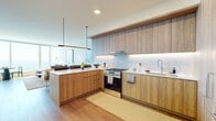 Located along Chicago's iconic Michigan Avenue, this thoughtfully designed one-bedroom, one-bathroom residence offers a refined urban living experience with sweeping views of Lake Michigan and Grant Park. The open-concept layout connects the kitchen and living areas seamlessly, maximizing the sense of space throughout.

The kitchen is a standout feature, showcasing warm wood-toned cabinetry extending floor to ceiling, a marble-inspired backsplash with under-cabinet lighting, stainless steel gas range, and a peninsula with white quartz countertops — ideal for both cooking and casual dining. Light wood flooring flows throughout the space, complementing the contemporary aesthetic.

The living room is anchored by expansive floor-to-ceiling windows that flood the room with natural light and frame breathtaking panoramic views of the lakefront. A dedicated dining nook sits beside the windows, making the most of the scenery.

The bedroom continues the view-forward design, with large windows overlooking Lake Michigan and Grant Park, creating a bright and serene retreat. A built-in closet provides ample storage.

The bathroom features marble-tiled walls and flooring, a dark wood vanity with white countertop, and a backlit mirror, delivering a clean, upscale finish. The entryway includes a tall built-in storage unit, completing this well-appointed residence.