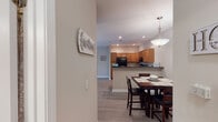 Located at 300 Caughman Farm Ln in Lexington, SC, this single-floor residence offers a thoughtfully designed layout with a warm, welcoming ambiance throughout. The open-concept living and dining area is anchored by wood-look flooring, neutral-toned walls, and a vaulted ceiling in the living room that enhances the sense of space. A sliding glass door floods the living area with natural light and provides views of the surrounding greenery. The kitchen is well-equipped with warm honey-toned cabinetry, dark countertops, black appliances including a range and refrigerator, a double-basin sink, and a peninsula with bar seating — ideal for casual dining or entertaining. Recessed lighting and a pendant light add to the kitchen's functional appeal. The dining area sits adjacent to the kitchen, providing a seamless flow for everyday living. The bedrooms feature plush carpeting, ceiling fans, and windows with blinds and curtain panels. The primary bedroom includes access to a walk-in closet. The bathrooms are finished with wood-look flooring, grab bars, and tub-shower combinations, reflecting a practical and accessible design. Overall, this residence combines comfortable living spaces with a clean, cohesive aesthetic throughout.