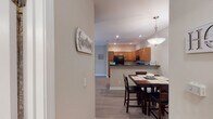Located at 300 Caughman Farm Ln in Lexington, SC, this single-floor residence offers a thoughtfully designed layout with a warm, welcoming ambiance throughout. The open-concept living and dining area is anchored by wood-look flooring, neutral-toned walls, and a vaulted ceiling in the living room that enhances the sense of space. A sliding glass door floods the living area with natural light and provides views of the surrounding greenery. The kitchen is well-equipped with warm honey-toned cabinetry, dark countertops, black appliances including a range and refrigerator, a double-basin sink, and a peninsula with bar seating — ideal for casual dining or entertaining. Recessed lighting and a pendant light add to the kitchen's functional appeal. The dining area sits adjacent to the kitchen, providing a seamless flow for everyday living. The bedrooms feature plush carpeting, ceiling fans, and windows with blinds and curtain panels. The primary bedroom includes access to a walk-in closet. The bathrooms are finished with wood-look flooring, grab bars, and tub-shower combinations, reflecting a practical and accessible design. Overall, this residence combines comfortable living spaces with a clean, cohesive aesthetic throughout.