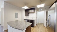 This single-floor residence offers a thoughtfully designed layout across two bedrooms and two bathrooms. The open-concept living and kitchen area serves as the heart of the home, featuring light hardwood-style flooring, recessed lighting, and a sliding door that provides natural light and outdoor access. The kitchen is equipped with dark espresso cabinetry, granite countertops, a central island with additional counter space, a stainless steel refrigerator, dishwasher, and pendant lighting overhead.

Both bedrooms feature neutral carpet flooring, ceiling fans with lighting, and windows with outdoor views. Each bedroom is paired with a dedicated closet fitted with wire shelving systems for organized storage. The bathrooms mirror the kitchen's design aesthetic, showcasing dark vanity cabinetry, granite countertops, and tiled tub-shower combinations with sliding glass enclosures.

A dedicated in-unit laundry area accommodates a full-sized washer and dryer with additional wire shelving above. A connecting hallway links all rooms efficiently. Throughout the residence, a neutral color palette and consistent finishes contribute to a clean, cohesive, and functional living environment.