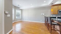 Located at 1804–1817 New Jersey Ave NW in Washington, DC, this two-story home offers a well-organized layout spread across two floors. The main level welcomes you with a bright entrance featuring hardwood flooring, neutral gray walls, and front-facing windows that bring in natural light. The open-concept kitchen and dining area form the heart of the first floor, showcasing warm wood cabinetry, dark granite countertops, a center island with bar seating, stainless steel appliances including a gas range, microwave, and refrigerator, and amber pendant lighting above. A staircase with a classic wood railing connects the two levels. The spacious living and dining areas feature gleaming hardwood floors and recessed lighting throughout. A bathroom on the main level includes classic tilework and a vanity. Upstairs, two carpeted bedrooms offer a comfortable retreat, each with neutral tones, white trim, and windows overlooking the neighborhood. The primary bedroom provides a generous footprint. A jetted soaking tub is a standout feature of one of the upper bathrooms. Additional conveniences include a dedicated laundry area, multiple closets, and two hallways ensuring smooth circulation throughout this practical and well-appointed DC home.