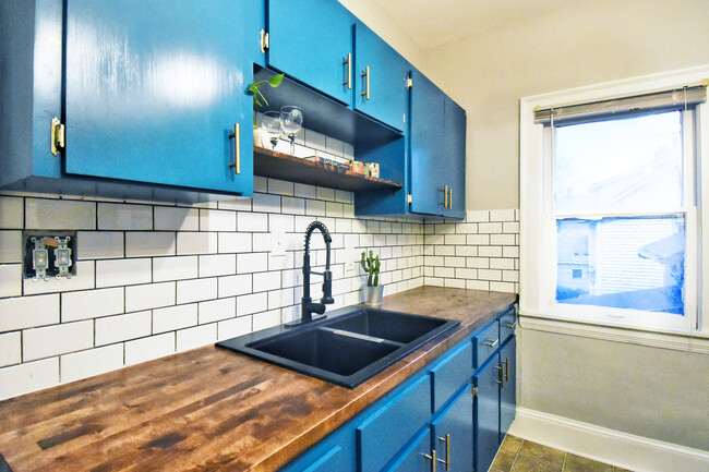 Vibrant kitchen with wooden countertop and shelving, stainless steel refrigerator and gas range - 10105 Burton Ave