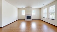 This well-appointed single-floor home in Brookfield, Wisconsin offers three bedrooms, two full bathrooms, and a thoughtfully designed layout. The open kitchen is a standout feature, showcasing rich medium-toned wood cabinetry, granite countertops, a granite-topped island with pendant lighting, and a full suite of stainless steel appliances including a refrigerator, range, microwave, and dishwasher. Durable hardwood-style flooring runs throughout the kitchen and flows into the living room, which is anchored by a tile-surround fireplace flanked by windows that bring in natural light and outdoor greenery views. The three bedrooms offer plush carpeting and windows overlooking lush surroundings, providing comfortable, quiet retreats. The primary bathroom features large-format tile flooring, warm wood cabinetry with granite counters, a framed mirror, and a walk-in glass-door shower. The second full bathroom mirrors this quality with similar finishes and includes a shower-tub combination. A hallway with a closet adds practical storage. The home's neutral color palette of warm beige tones, consistent trim work, and quality finishes throughout give the space a cohesive and inviting character suited for comfortable everyday living.