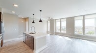 Located at 838 Morrison Dr in Charleston, SC, this single-floor residence offers a thoughtfully designed open-concept layout with modern finishes throughout. Light wood-tone flooring flows seamlessly across the entire unit, enhancing the bright and airy ambiance created by abundant natural light pouring through large windows.

The kitchen serves as a central highlight, featuring a generous island with a white quartz countertop, stainless steel appliances including a range, microwave, and refrigerator, sleek dark cabinetry, a tile backsplash, and a professional-style pull-down faucet over a deep stainless sink. Industrial-style pendant lights above the island add a contemporary touch.

The open living area is expansive, bathed in natural light from a bank of large windows and fitted with a ceiling fan. Glass doors lead directly to a private balcony with views of the Charleston skyline and surrounding neighborhood.

Bedrooms are well-proportioned with ample closet space and ceiling fans. A hallway connects the private quarters to the main living areas. Two bathrooms offer refined finishes — one features a soaking tub with floor-to-ceiling marble-style tile surround, while the other includes a glass-enclosed shower, a long floating vanity with white countertop, and wood-look tile flooring.