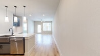 Located at 750 W Grand Pkwy S in Katy, TX, this well-appointed one-bedroom, one-bathroom unit offers a thoughtfully designed layout with modern finishes throughout. Light wood-tone flooring flows through the main living areas, complemented by neutral wall tones that create a bright, clean aesthetic.

The open-concept kitchen and living area serves as the heart of the unit. The kitchen features gray shaker-style cabinetry with matte black hardware, a large white quartz island with an undermount sink and matte black faucet, stainless steel appliances including a French door refrigerator, electric range, and built-in microwave, and elegant pendant lighting overhead.

The bedroom offers plush wall-to-wall carpeting, a ceiling fan, and a window with natural light. A dedicated closet provides built-in open shelving for organized storage.

The bathroom is generously sized with light wood flooring, gray cabinetry with white quartz countertops, a dual undermount sink with matte black fixtures, a large frameless glass walk-in shower with marble-style tile surround, and a wide vanity mirror.

A private balcony with a glass-paneled door extends the living space outdoors, providing outdoor views. The unit combines modern design with functional living in a convenient Katy location.