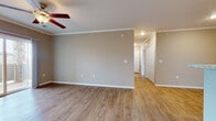 This single-floor residence offers a thoughtfully designed open-concept layout that seamlessly connects the main living areas. The living room is finished with warm wood-look luxury vinyl flooring, crown molding, and a ceiling fan, while a sliding glass door fills the space with natural light and provides direct access to an outdoor patio with neighborhood views. The kitchen is well-equipped with white shaker-style cabinetry, granite-look countertops, stainless steel appliances including a refrigerator, range, microwave, and dishwasher, plus a breakfast bar peninsula that enhances functionality. Recessed lighting and crown molding add a polished finish to the kitchen area. A hallway connects the living space to multiple bedrooms, each featuring plush neutral carpet, warm-toned walls, and windows that bring in natural light and views of the surrounding neighborhood. The bathroom is fitted with a white vanity, granite-look countertop, a large mirror, and clean white cabinetry with brushed nickel hardware. Throughout the residence, consistent neutral tones, white trim, and quality finishes create a cohesive and inviting atmosphere suited for comfortable everyday living.