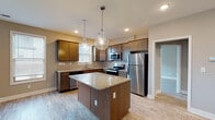 Located at 299 Squires Cir in Lexington, Kentucky, this two-story home offers a thoughtfully designed layout with quality finishes throughout. The kitchen serves as a central highlight, featuring rich dark-toned cabinetry, granite countertops, a subway tile backsplash, and a full suite of stainless steel appliances including a refrigerator, range, microwave, and dishwasher. A center island with pendant lighting adds both function and style, while natural light filters in through multiple windows fitted with blinds. Light wood-style flooring flows through the main living areas, complementing the neutral wall tones that create a clean, cohesive aesthetic. The bedrooms are generously sized, with several featuring plush carpet, ceiling fans, and ample natural light from well-placed windows. Bathrooms are finished with granite-topped vanities, dark wood cabinetry, and tile flooring, with at least one full bath offering a tub-shower combination. A dedicated laundry room includes a full-size washer and dryer. Additional storage is available via a walk-in closet with wire shelving. The home's consistent use of neutral tones, granite surfaces, and modern fixtures presents a move-in-ready interior suitable for a variety of lifestyles.