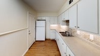 This single-floor, two-bedroom, one-bathroom residence offers a practical and comfortable layout designed to maximize livable space. Warm wood-look flooring flows consistently throughout the unit, lending a cohesive and inviting aesthetic to every room.

The living area is generously sized, featuring a textured ceiling, a ceiling fan with integrated lighting, and a window fitted with horizontal blinds that allows natural light to brighten the space. The clean, neutral wall tones provide a versatile backdrop adaptable to a variety of furnishing styles.

The kitchen is efficiently laid out with ample white cabinetry offering generous storage above and below the counters. A stone-tile backsplash adds a refined touch, complementing the light countertops and stainless steel double-basin sink. The kitchen also features durable wood-look flooring and includes a full-size refrigerator.

Both bedrooms continue the wood-look flooring and neutral color palette, each equipped with ceiling fans and windows with blinds for natural light and ventilation. The rooms offer comfortable dimensions suitable for standard bedroom furnishings.

The bathroom is clean and well-maintained, featuring a full soaking tub and shower combination with chrome fixtures, a vanity with storage, and a mirror. The tiled accent detail adds a subtle decorative element. The overall unit presents a functional, move-in-ready living environment.