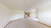 Located in Auburn, WA, this well-appointed one-bedroom, one-bathroom residence offers a thoughtfully designed single-floor layout. The open-concept living room is a standout space, featuring a classic white-mantled fireplace flanked by two windows that flood the room with natural light and offer views of the surrounding greenery. Plush carpeting and neutral walls create a warm, inviting ambiance throughout the living areas. The kitchen is efficiently laid out in a galley style, showcasing warm oak cabinetry, ample counter space, stainless steel appliances including an electric range and dishwasher, and durable hardwood-style flooring. A pass-through view from the kitchen opens directly to the living room, enhancing the sense of openness. Sliding glass doors lead to a private balcony, extending the living space outdoors. The generously sized bedroom is carpeted and filled with natural light through a large window, complete with baseboard heating. A dedicated closet provides practical storage. The bathroom features a warm wood vanity with a single sink, a well-lit mirror, and a full soaking tub with tiled surround. Rich wood baseboards throughout tie the design together cohesively.
