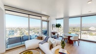 This contemporary high-rise residence is designed with a clean, modern aesthetic throughout. The open-plan living and dining area serves as the heart of the home, anchored by expansive floor-to-ceiling windows that frame sweeping panoramic views of the cityscape and distant mountain ranges. Natural light floods the space, creating a bright and airy atmosphere, while sliding glass doors connect the living area to a private balcony — ideal for taking in the elevated vistas. Light hardwood flooring runs throughout, complementing the crisp white walls and adding warmth to the minimalist design.

The kitchen is fitted with flat-front cabinetry in a soft grey finish, stainless steel appliances, a gas range, and a herringbone-patterned tile backsplash, all accented by an oversized window framing the surrounding skyline. The dining area is positioned at the corner of the unit, maximizing the views with two full-height windows.

Both bedrooms are generously proportioned, each offering large corner or full-width windows with open city and mountain views and ample closet space. The bathrooms feature large-format tile flooring, floating dark-toned vanities, and a walk-in shower. Well-lit hallways with recessed lighting and louvered closet doors provide functional connectivity throughout the residence.