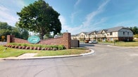 Huntington Place is a well-established residential rental community that makes a strong first impression with its distinguished brick entrance monument, lush landscaping, and colorful seasonal plantings. The community's exterior architecture is characterized by classic Tudor-style design elements, including decorative half-timbering, pitched rooflines, and multi-pane windows that lend the buildings a timeless, cohesive aesthetic. Residents are greeted by a gently curving roadway lined with mature trees and manicured green lawns, creating a peaceful, park-like setting throughout the grounds. The dedicated leasing office is housed in a charming Tudor-style structure that mirrors the community's residential buildings, featuring brick accents, lantern-style lighting, and inviting entryway plantings. Accessible parking is available directly adjacent to the office. The facility also includes dedicated maintenance and storage areas, equipped with shelving systems that house cleaning supplies, maintenance materials, and pool equipment infrastructure, reflecting the community's commitment to ongoing upkeep and operational readiness. With its attractive curb appeal, thoughtfully maintained common areas, and practical on-site facilities, Huntington Place presents a well-rounded community designed to support comfortable residential living.