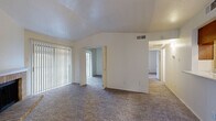 Located at 2626 Thousand Oaks Dr in San Antonio, TX, this 2-bedroom, 1-bathroom single-floor unit offers a well-organized and functional layout. The living room is a standout space, featuring vaulted ceilings that lend an open, airy feel, soft carpeting underfoot, and a classic brick fireplace framed by a white mantel — creating a warm and inviting focal point. Vertical blinds cover a large sliding door, allowing natural light to filter through. The adjacent dining area features warm hardwood-style flooring and a pendant light fixture, with a window offering a view of the greenery outside. The galley-style kitchen is efficiently designed with rich wood cabinetry, light countertops, a double sink, and black appliances including a refrigerator, range, and built-in microwave. A hallway connects the living areas to the two carpeted bedrooms, each offering natural light through windowed blinds and a comfortable, quiet atmosphere. The bathroom is clean and practical, featuring wood vanity cabinetry, a light countertop, and a shower/tub combination. A dedicated closet and hallway complete the layout, making this a well-appointed and efficient home.