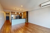 Located at 106 Denny Way in Seattle's vibrant South Lake Union neighborhood, this well-appointed one-bedroom, one-bathroom unit delivers a thoughtfully designed modern living experience. Warm hardwood flooring flows throughout the space, unifying each room with a cohesive, contemporary aesthetic.

The open-concept kitchen and living area serves as the heart of the unit. The kitchen is a standout, featuring rich wood cabinetry, a dark stone countertop island with an undermount sink, stainless steel appliances including a French door refrigerator, and elegant pendant lighting. Built-in open shelving adds both function and visual interest. The adjacent living area offers generous open space, ideal for flexible furniture arrangements.

The bedroom is a comfortable, light-filled retreat with a large picture window that brings in natural light and city views, complemented by a wall-mounted mini-split HVAC unit for year-round climate control. A dedicated closet provides practical storage.

The bathroom is clean and modern, with full white-tiled tub and shower surround, a wood-accented vanity with white countertop, and neutral tile flooring. A frosted glass sliding door is a sleek design detail visible from the hallway. The unit also includes multiple hallway spaces that connect each room efficiently.