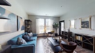 Located at 800 Baldwin Dr in Grandview Heights, Ohio, this single-floor unit showcases a thoughtfully designed layout with modern finishes and a cohesive contemporary aesthetic throughout. The open-concept kitchen is a standout feature, equipped with dark espresso cabinetry, stainless steel appliances including a refrigerator, microwave, and range, a white subway tile backsplash, and a granite-topped island with bar seating. Pendant lighting and track lighting add both function and style to the space. Rich wood-look flooring runs throughout the main living areas, complementing the kitchen's bold, dark color palette. The living room is bright and welcoming, with multiple large windows dressed in sheer curtains that allow generous natural light to fill the room. The bedrooms feature plush carpeting for added comfort. The primary bedroom includes a walk-in closet, while the secondary bedroom offers a well-sized window with outdoor views. The bathroom is finished with tile flooring, a dark vanity with a white countertop, and a glass-enclosed walk-in shower. Bold black interior doors provide a striking design accent carried consistently throughout the unit, tying together its modern, upscale character.