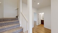 Located at 12890 S Black Bob Rd in Olathe, Kansas, this two-story home offers four bedrooms and five bathrooms across a thoughtfully designed layout. The main floor houses the kitchen and living area, a bathroom, and core utility spaces, while the upper floor—the larger of the two levels—accommodates the bedrooms, additional bathrooms, and a dedicated laundry room.

The kitchen is a standout feature, showcasing rich walnut-toned cabinetry paired with quartz countertops, a tile backsplash, stainless steel appliances, and a central island with an undermount sink. Light hardwood-style flooring runs throughout the main living areas, lending a warm, cohesive feel.

The bathrooms mirror the kitchen's modern aesthetic, featuring dark wood vanities with quartz countertops and large mirrors. The primary bathroom includes a double-sink vanity. Bedrooms are carpeted for comfort, with the primary bedroom offering a walk-in closet, ceiling fan, and natural light from well-placed windows. Additional bedrooms are similarly carpeted and accessible via a carpeted staircase with white-painted railings. The dedicated laundry room on the upper floor includes a full-size washer and dryer with overhead shelving. Throughout, the home maintains a clean, contemporary palette of white walls and modern fixtures.