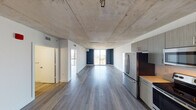 Located on the 11th floor of RAM Miami River at 35 SW 6th Ave, Unit 1108 is a contemporary residential unit that blends industrial design elements with modern finishes. The open-concept layout is anchored by striking exposed concrete ceilings that lend an urban, loft-inspired character throughout the space. Durable wood-tone luxury vinyl plank flooring runs continuously across the unit, complementing the clean white walls and creating a cohesive, polished aesthetic.

The kitchen is fully equipped with stainless steel appliances, including a French door refrigerator, electric range, built-in microwave, and dishwasher. Sleek, textured gray cabinetry extends floor to ceiling, providing ample storage, while light-toned countertops and a deep single-basin sink complete the functional workspace.

The expansive living area benefits from generous natural light, courtesy of large floor-to-ceiling windows that frame sweeping views of the Miami cityscape and surrounding greenery. Navy blue accent walls punctuate key areas, adding depth and visual interest to the otherwise neutral palette.

A separate bedroom features a closet with louvered doors and the same exposed concrete ceiling treatment, maintaining design continuity. The unit's single-floor layout ensures an efficient and accessible flow between all areas, making it a well-appointed urban residence in the heart of Miami.
