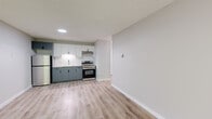 Located at 26 High St in Rensselaer, NY, this well-appointed one-bedroom, one-bathroom unit offers a clean, modern aesthetic across a single floor. Light wood-style vinyl plank flooring runs throughout, complementing the neutral gray walls and crisp white trim to create a bright, cohesive atmosphere.

The open living area is a standout feature, anchored by a large sliding glass door and wide window that frame views of surrounding greenery, filling the room with natural light. A baseboard heating system runs along the perimeter, and the textured ceiling adds subtle dimension to the space.

The kitchen has been tastefully updated with two-tone cabinetry — soft white upper cabinets and muted sage-green lower cabinets — paired with granite-look countertops and a classic white subway tile backsplash. Stainless steel appliances, including a range with overhead ventilation and a refrigerator, complete the functional and stylish cooking space.

The bedroom is a comfortable, well-proportioned retreat featuring a window with blinds for natural light and privacy, along with continued wood-style flooring and neutral walls.

The bathroom features a tub/shower combination enclosed with crisp white subway tile and dark grout, offering a clean, timeless look. Overall, this unit presents a modern, move-in-ready living experience in a convenient Rensselaer location.