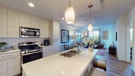 Located at 7777 Westside Dr in San Diego, CA, this single-floor residence offers a thoughtfully designed open-concept layout that seamlessly connects the kitchen, dining, and living areas. The kitchen is a standout feature, boasting a large center island with a quartz countertop, an undermount sink, and pendant lighting overhead. Crisp white cabinetry extends to the ceiling, providing ample storage, while stainless steel appliances — including a gas range, built-in microwave, and refrigerator — complete the modern aesthetic. Warm hardwood-style flooring flows throughout the main living areas, adding continuity and warmth. The living room is bright and welcoming, with a large window that draws in natural light and offers views of the surrounding greenery. Soft, neutral-toned walls and contemporary lighting create a relaxed and inviting ambiance. The bedroom is a comfortable retreat, featuring plush carpeting, pendant lighting, and well-proportioned windows dressed with floor-to-ceiling drapes. The bathroom is finished with a clean, modern aesthetic, featuring a white quartz vanity, a large mirror, and wood-toned flooring. A walk-in closet is accessible directly from the bathroom, offering generous storage. Overall, the space presents a cohesive and contemporary design with quality finishes throughout.