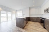 Located at 11805 30 Avenue SW in Edmonton, Alberta, this modern single-floor unit offers four bedrooms and two bathrooms with a thoughtfully designed layout. Light-toned hardwood flooring flows consistently throughout the space, complementing the crisp white walls and clean-lined aesthetic.

The kitchen is a standout feature, showcasing a two-tone cabinetry design with dark wood lower cabinets and white upper cabinets, paired with light quartz countertops and a central island with an integrated sink. Stainless steel appliances, including a range, dishwasher, and over-the-range microwave, complete the contemporary look. Recessed lighting and a window bring brightness to the space.

The four bedrooms are well-proportioned, each featuring large windows that invite natural light and offer views of the surrounding area. The primary bedroom includes a dedicated closet with built-in shelving and rack storage. Additional bedrooms provide ample space and similarly benefit from natural light.

Both bathrooms are finished with large-format marble-look tile flooring, dark wood vanities with white countertops, and full tub-shower combinations. The hallway connects all rooms efficiently, contributing to the unit's practical and streamlined flow. Overall, the space presents a modern, neutral palette ideal for comfortable everyday living.