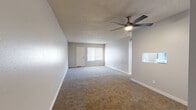 Located at 7700 E Speedway Blvd in Tucson, Arizona, this single-floor unit offers a well-organized layout with a thoughtful blend of updated finishes and comfortable living spaces throughout. The spacious living area features plush wall-to-wall carpeting, a textured ceiling, and a ceiling fan with integrated lighting. Natural light flows in through a large window fitted with blinds, and the room provides ample space for a variety of furniture arrangements. The kitchen stands out with its contemporary two-tone cabinetry — white upper cabinets paired with gray lower cabinets — complemented by a blue subway tile backsplash, white countertops, light wood-look luxury vinyl flooring, and stainless steel appliances including a refrigerator and range. The bedrooms are carpeted and bright, each with a window that allows natural light to fill the space. Two full bathrooms serve the unit; one features a tub-shower combination with chrome fixtures and a vanity with a mirrored medicine cabinet, while the second includes a stand-alone shower with built-in shelving and a matching gray vanity. Clean neutral tones, white trim, and consistent finishes throughout give the space a cohesive, move-in-ready feel.