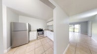 Located at 4765 Lake Arjaro Dr in West Palm Beach, FL, this single-floor, 2-bedroom, 2-bathroom home offers a clean and functional layout with consistent light tile flooring throughout. A central hallway connects the main living areas, leading to a bright combined living and dining room with large sliding glass doors that invite natural light and provide access to a private balcony with outdoor views.

The kitchen is well-appointed with white cabinetry, granite-style countertops, and a full suite of stainless steel appliances including a refrigerator, electric range, and dishwasher. A pass-through window connects the kitchen to the living area, enhancing the open feel of the space.

The spacious primary bedroom offers natural light through a window with blinds, while the second bedroom is equally bright and similarly finished. Both rooms feature neutral walls and tile flooring. Two closets provide ample storage throughout the home.

The bathrooms are finished with white vanities and marble-style countertops. One bathroom features a soaking tub with striking floor-to-ceiling wood-plank tile surround. In-unit laundry with a stacked washer and dryer adds convenience. The overall aesthetic is clean, bright, and move-in ready.