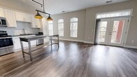 This contemporary apartment boasts a thoughtfully designed layout that maximizes space and functionality. The heart of the home is a gourmet kitchen, equipped with stainless steel appliances, white cabinetry, and a sleek subway tile backsplash. A large center island with pendant lighting serves as both a prep area and casual dining space.

The open-concept living area features wood-look flooring and a modern electric fireplace, creating a cozy yet sophisticated atmosphere. Large windows and French doors flood the space with natural light and provide access to an outdoor area.

The bedroom offers plush carpeting and arched windows, while the bathroom showcases a marble-inspired tile shower. Ample storage solutions include walk-in closets with wire shelving systems.

Additional highlights include a ceiling fan for improved air circulation, recessed lighting, and neutral wall colors throughout. The unit's layout, as seen in the 3D floor plan, reveals a well-organized space that seamlessly blends comfort with style.