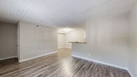 Located at 874 Yorkchester Drive in Houston, TX, this single-story residence offers three bedrooms and two bathrooms across a well-organized floor plan. The living room is bright and open, featuring wood-look laminate flooring and a large window that invites natural light and outdoor views. A half-wall peninsula connects the living area to the galley-style kitchen, which is equipped with white cabinetry, granite-look countertops, a double-basin sink, and black appliances including a range and dishwasher. The kitchen's wood-look flooring continues the cohesive aesthetic throughout the common areas. The spacious primary bedroom offers generous proportions, a ceiling fan, and a dedicated closet. The additional bedrooms are carpeted and feature ceiling fans, with one room benefiting from a window overlooking the exterior. Both bathrooms are finished with granite-topped vanities, grey cabinetry, and wood-look flooring. One bathroom includes a tub-shower combo with white tile surround. Neutral warm-beige tones are used consistently throughout, creating a clean and cohesive ambiance. The layout is practical and functional, making efficient use of the available space.