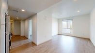 This thoughtfully designed 3-bedroom, 2-bathroom single-floor unit is located at 8811 Sepulveda Blvd in Los Angeles, CA. The interior features a clean, modern aesthetic with light wood-tone flooring and crisp white walls carried consistently throughout the space. The combined kitchen and living area serves as the heart of the home, with the kitchen outfitted with sleek gray cabinetry, white countertops, a stainless steel refrigerator, range, and an under-cabinet range hood — offering a contemporary and functional cooking environment. The living area benefits from a large window fitted with roller shades, allowing ample natural light. Each of the three bedrooms is well-proportioned, with large windows framing outdoor views of the surrounding Los Angeles neighborhood. Several bedrooms include sliding double-door closets, providing practical storage, while four closets are distributed throughout the unit. A hallway connects the rooms efficiently. The two bathrooms maintain the same clean, minimalist design, each featuring a soaking tub with shower, white tile surround, vanity with sink, and wood-look flooring. One bathroom is notably more spacious and includes accessibility-friendly grab bars. The overall ambiance is bright, airy, and move-in ready.