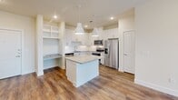 Located at 14119 Montfort Dr in Dallas, TX, this single-story, 3-bedroom, 2-bathroom home offers a well-designed layout across a comfortable footprint. The kitchen is a standout feature, showcasing white shaker cabinetry extending to the ceiling, granite countertops, a subway tile backsplash, stainless steel appliances including a French door refrigerator and electric range, and wood-look flooring. A central island with pendant lighting adds both function and style, while a built-in desk nook provides a dedicated workspace. Each of the three bedrooms is finished with plush carpeting and features windows with blinds that invite natural light and outdoor views. Ceiling fans are present in multiple bedrooms for added comfort. The primary bedroom includes a spacious walk-in closet outfitted with built-in shelving and double hanging rods. One secondary bedroom features double closet doors, offering generous storage. Both bathrooms are finished with granite vanity countertops, white cabinetry, and wood-look flooring. One bathroom includes a tiled tub-shower combination with classic white subway tile. A connecting hallway ties all rooms together efficiently, completing this clean, modern, and move-in-ready home.