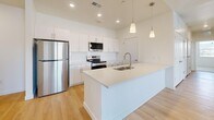 Located on S Cross Hollow Rd in Cedar City, Utah, this single-story, 3-bedroom, 2-bathroom home offers a well-designed layout with modern finishes throughout. The open-concept kitchen and living area serves as the heart of the home, highlighted by vaulted ceilings, recessed lighting, and warm light wood flooring. The kitchen is outfitted with white shaker-style cabinetry, a large center island with a built-in sink, white quartz countertops, stainless steel appliances, and stylish pendant lighting. Both bathrooms continue the clean aesthetic with light wood flooring, white vanities with quartz countertops, brushed nickel hardware, and tub-shower combinations. The three bedrooms feature plush neutral carpet and bright white walls, with select rooms offering outdoor views of the surrounding Cedar City landscape through large windows. Two closets provide dedicated storage, including a spacious walk-in closet with built-in shelving and hanging rods. A hallway connects the private sleeping quarters to the main living areas. Additional utility space with built-in cabinetry and countertops adds functional versatility. The home's consistent use of white tones and natural wood elements creates a bright, cohesive, and inviting atmosphere throughout.