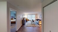 Located at 10700 Hampshire Ave S in Bloomington, Minnesota, this single-floor residence offers a thoughtfully designed layout with a comfortable blend of modern finishes and functional living spaces. The living room serves as the centerpiece of the home, featuring wood-style flooring, a textured ceiling, and a large sliding glass door framed by vertical blinds that floods the space with natural light and provides views to the outdoors. The kitchen is well-equipped with white shaker cabinetry, granite-style countertops, stainless steel appliances including a refrigerator and range, and a subway tile backsplash. A breakfast bar offers casual seating, complementing the dedicated dining nook nearby, which provides an intimate setting for meals. The two bedrooms are carpeted for comfort, each featuring windows that bring in natural light and wall-mounted climate control units. One bedroom features a herringbone wood-panel headboard wall, while the other offers a cozy, understated aesthetic. The full bathroom includes a single-sink vanity with white cabinetry, wood-style flooring, and a shower-tub combination. Throughout the residence, neutral tones and consistent flooring create a cohesive and inviting atmosphere.