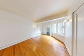 Located in the Belltown neighborhood of Seattle, WA, this single-floor unit at 2205 2nd Ave offers a well-organized layout that makes efficient use of its intimate footprint. The entrance hallway, framed by clean white millwork and crisp trim detailing, leads directly into the living spaces and sets a consistent, classic tone throughout.

The living room is the heart of the unit, featuring warm-toned hardwood floors that run throughout the main living areas, bright white walls, and a large window that draws in natural light and provides views of the surrounding urban streetscape. Baseboard heating units are positioned along the walls, ensuring comfortable warmth. Structural beam detailing adds subtle architectural character to the ceiling.

The kitchen is a separate, defined space with white cabinetry, open counter space, and a freestanding range — functional and straightforward in its design. Two closets provide practical storage solutions within the unit.

The bathroom is finished in classic white subway tile, featuring a full soaking tub with an overhead shower, a wall-mounted vanity with mirror, and terrazzo-style flooring — a nod to the building's period character.

Throughout, the unit maintains a clean, neutral palette of whites and natural wood tones, creating a bright and cohesive atmosphere well-suited to urban living in one of Seattle's most walkable neighborhoods.