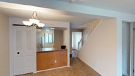 This three-floor residence offers a practical and comfortable layout designed to maximize functionality across every level. The lowest level houses a built-in garage with concrete block walls and an automatic door, providing secure parking and additional storage. Adjacent to the garage is a utility area containing washer and dryer hookups, a utility sink, a water heater, and HVAC equipment, all accessible within the lower level.

The main living floor features an open layout connecting the living area to a pass-through kitchen. The kitchen is equipped with warm wood cabinetry, granite-style countertops, a full suite of white appliances including a refrigerator, electric range, and built-in microwave, along with hardwood-style flooring. The living area is generously sized with carpet flooring and a sliding glass door that invites natural light and outdoor views.

The upper floor hosts carpeted bedrooms, each featuring closets and ceiling fans with lighting. The bathrooms are well-appointed, with one featuring a single vanity with a large mirror and warm cabinetry, and another offering a full tub-shower combination with tile flooring and a wood-toned vanity.