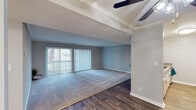 This single-floor residence offers a thoughtfully designed layout with a cohesive neutral color palette of soft grays and whites that creates a calm, inviting atmosphere throughout. The spacious living area is anchored by a combination of plush carpet and wood-look flooring, complemented by a vaulted ceiling detail with a ceiling fan and sliding glass doors fitted with vertical blinds that bring in ample natural light. A built-in shelf nook adds a decorative accent to the living space, while crown molding and decorative columns lend architectural character.

The galley-style kitchen is outfitted with white cabinetry, brushed nickel hardware, neutral countertops, and wood-look flooring, providing a clean and efficient workspace. The bedrooms are carpeted and generously sized, each featuring crown molding, soft gray walls, and mirrored sliding closet doors that enhance the sense of space. Windows with outdoor greenery views add a refreshing natural touch.

The bathrooms are finished with wood-look flooring and clean white fixtures. One bathroom includes a wide vanity with white cabinetry, a large mirror, and brushed nickel accents, while the other offers a glass-enclosed shower stall. Together, these spaces present a comfortable and well-maintained residence with consistent, modern finishes throughout.