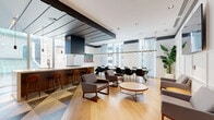 Located at 1180 Rue de Bleury in the heart of Montréal, this sophisticated lounge and kitchen amenity space is divided into two thoughtfully designed zones that together offer a compelling blend of functionality and high-end aesthetics. The kitchen and dining area is bright and modern, featuring a striking geometric-patterned tile floor, a substantial island with warm wood cabinetry and bar seating, and a full wall of integrated appliances. Floor-to-ceiling windows flood the space with natural light and frame views of the surrounding cityscape, while linear pendant fixtures suspended above a large communal dining table create an inviting atmosphere for gatherings. A seating area near the entrance provides a transitional lounge space anchored by a wall-mounted display screen. The second zone is a richly appointed lounge that contrasts boldly with the kitchen's brightness. Deep teal walls, a layered circular ceiling with gold trim and globe pendants, and large round mirrors set a dramatic, boutique-hotel ambiance. A curved, blush-pink banquette wraps around black marble-topped tables, complemented by plush velvet armchairs in teal and blush tones. A compact wet bar with dark stone accents and a floor-length burgundy curtain complete this intimate retreat. Light oak hardwood flooring flows throughout, unifying both areas.