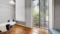 Located at 800 James Ave in Scranton, PA, this one-bedroom, one-bathroom unit is thoughtfully laid out across two floors. The main level features warm hardwood flooring throughout the combined kitchen and living area. Large floor-to-ceiling windows fitted with vertical blinds flood the space with natural light and offer lush, tree-lined views of the surrounding greenery, creating a bright and inviting atmosphere. The kitchen is well-appointed with white cabinetry, dark countertops, a coil-burner range, and a full-size refrigerator, providing ample storage and prep space. Exposed brick accents in the living area add a touch of industrial character, complementing the otherwise clean and modern aesthetic. The upper floor hosts the generously sized bedroom, featuring carpet flooring, exposed ceiling beams, and two mirrored closets that offer substantial storage. The bedroom connects directly to the full bathroom, which includes a white vanity with cabinetry, a wall-mounted mirror, and decorative tile flooring. The overall ambiance of this unit is cozy yet functional, blending practical design elements with warm, natural touches that make it a comfortable and well-rounded living space.