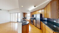 Located at 50 S Grove Ave in Elgin, Illinois, this thoughtfully designed single-floor home offers three bedrooms and three bathrooms across a generous, well-organized floor plan. The open-concept living and kitchen area serves as the heart of the home, featuring warm hardwood flooring that reflects natural light streaming in through multiple windows. The kitchen is a standout, equipped with stainless steel appliances including a gas range and French door refrigerator, rich wood cabinetry, dark granite countertops with a tile backsplash, and a peninsula with a built-in sink — ideal for both everyday cooking and entertaining. The living area is bright and expansive, with clean white walls and a smooth flow into the hallways and bedrooms. The three bedrooms are finished with plush carpeting, ceiling fans, and windows that bring in natural light. The primary bedroom includes a private en-suite bathroom featuring a dual-sink vanity with wood cabinetry, a soaking tub with tile surround, and tile flooring. Additional bathrooms are finished in a clean, neutral palette with tile floors. Two closets and two hallways provide practical storage and seamless circulation throughout the home.