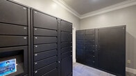 Located in Columbia, SC, this package room is a purpose-built amenity space designed to streamline parcel management for residents. The room is outfitted with multiple banks of Luxer One smart package lockers finished in matte black, offering numerous individually numbered compartments of varying sizes to accommodate deliveries of all dimensions. The lockers are arranged efficiently along the walls, maximizing storage capacity within the compact footprint of the room.

The space features neutral gray walls, crown molding details, and low-pile carpet tiles in a subtle geometric pattern, lending a clean and polished aesthetic. A set of warm-toned wood cabinetry mounted on the wall provides additional storage, complementing the darker tones of the locker units. A full-light entry door with a multi-pane glass panel allows natural light to filter into the room while providing a clear view to the exterior.

A cork bulletin board is mounted near an interior door, serving as a communication point for residents. The room is accessed via a keyed interior door with a classic six-panel design. Overhead recessed lighting ensures the space is well-lit at all times. Overall, the room is thoughtfully designed to provide a secure, organized, and easily accessible hub for package retrieval.