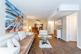 This single-floor residence in Topeka, Kansas offers a well-organized layout designed for comfortable living. The living room serves as the heart of the home, featuring rich hardwood-style flooring, a tufted sofa, modern white accent chairs, and a mirrored glass coffee table. A bold large-format painting adds a striking artistic focal point to the space, lending it a curated, contemporary feel. A ceiling fan provides additional comfort in the adjoining dining area, which connects seamlessly to the kitchen. The kitchen is outfitted with dark cabinetry, granite-look countertops, and a full suite of stainless steel appliances including a refrigerator, electric range, and over-the-range microwave, all set atop light tile flooring. The primary bedroom is generously sized with plush carpeting, a window for natural light, and direct access to a private en-suite bathroom featuring a walk-in tiled shower and dark vanity cabinetry. A second bathroom mirrors this aesthetic with a full tub-shower combo surrounded by large-format tile. Additional bedrooms offer carpeted floors, ample natural light from well-positioned windows, and versatile layouts suitable for a variety of needs. The overall ambiance throughout the home is warm and inviting, with neutral tones, tasteful décor, and a cohesive design that balances comfort and style.