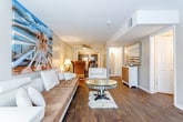 This single-floor residence in Topeka, Kansas offers a well-organized layout designed for comfortable living. The living room serves as the heart of the home, featuring rich hardwood-style flooring, a tufted sofa, modern white accent chairs, and a mirrored glass coffee table. A bold large-format painting adds a striking artistic focal point to the space, lending it a curated, contemporary feel. A ceiling fan provides additional comfort in the adjoining dining area, which connects seamlessly to the kitchen. The kitchen is outfitted with dark cabinetry, granite-look countertops, and a full suite of stainless steel appliances including a refrigerator, electric range, and over-the-range microwave, all set atop light tile flooring. The primary bedroom is generously sized with plush carpeting, a window for natural light, and direct access to a private en-suite bathroom featuring a walk-in tiled shower and dark vanity cabinetry. A second bathroom mirrors this aesthetic with a full tub-shower combo surrounded by large-format tile. Additional bedrooms offer carpeted floors, ample natural light from well-positioned windows, and versatile layouts suitable for a variety of needs. The overall ambiance throughout the home is warm and inviting, with neutral tones, tasteful décor, and a cohesive design that balances comfort and style.