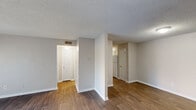 Located at 1504 Fernwood-Glendale Rd in Spartanburg, SC, this one-bedroom, one-bathroom residence offers a practical and comfortable single-floor layout. The living room is a standout space, featuring rich hardwood-style flooring and a full-width sliding glass door fitted with vertical blinds that floods the room with natural light and provides views of the surrounding greenery. A hallway connects the living area to the rest of the home, maintaining a clear and functional flow throughout. The kitchen is positioned centrally within the layout and includes a refrigerator and range, with white cabinetry visible from the adjoining spaces. The bedroom is a generously sized room finished with soft carpet flooring and a window that allows in natural light. It provides direct access to a dedicated closet outfitted with built-in shelving rods for organized storage. The full bathroom features wood-style flooring, a white vanity with mirror, and a well-lit vanity fixture above. Throughout the home, textured ceilings, neutral warm-toned walls, and clean white trim create a cohesive and understated aesthetic. This residence offers an efficient and well-organized floor plan suited for comfortable everyday living.
