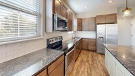 Located at 221 Trowbridge St, Unit 301 in Grand Rapids, MI, this thoughtfully designed 3-bedroom, 4-bathroom residence offers a well-appointed single-level layout. The open-concept living, dining, and kitchen area serves as the heart of the home, featuring warm wood-style flooring, recessed lighting, and a generous flow of natural light through multiple windows with blinds. The kitchen is a standout, showcasing rich dark wood cabinetry, granite countertops, a subway tile backsplash, a central island with pendant lighting, and a full suite of stainless steel appliances. A hallway connects the private quarters, where three carpeted bedrooms each offer comfortable proportions and ample closet space — the unit includes an impressive seven closets total. The primary bedroom provides a quiet retreat with its own dedicated bathroom. The four bathrooms are finished with stone-tile flooring, dark wood vanities, and clean white fixtures including tub-shower combinations. Neutral warm-toned walls and crisp white trim carry consistently throughout, creating a cohesive and modern aesthetic. The unit's practical layout and quality finishes make it a well-rounded residence in the heart of Grand Rapids.