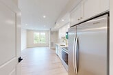 Unit 303 at 499 Atkinson Ave in Stoughton, MA is a thoughtfully designed single-floor unit that maximizes functionality within a compact footprint. The open layout seamlessly connects the living area and kitchen, creating an efficient and cohesive living space.

The kitchen is outfitted with crisp white shaker cabinetry, white quartz countertops, and a full suite of stainless steel appliances, including a refrigerator, electric range, built-in microwave, and dishwasher. A gold-finish faucet at the undermount sink adds a refined accent, while recessed lighting and a wall-mounted mini-split system ensure comfort and convenience. An in-unit washer and dryer are also included.

The living area is bright and airy, featuring light-toned hardwood flooring that runs throughout the unit, warm neutral walls, and a large window that frames a lush, tree-lined view, allowing natural light to fill the space. Recessed lighting and clean panel-style interior doors with matte black hardware contribute to the unit's modern, polished aesthetic.

The bathroom is finished with light tile flooring, a white vanity with gold hardware, a framed mirror with overhead lighting, and a shower-tub combination, maintaining the same refined, contemporary style found throughout the unit.
