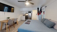 Located at 425 Second St N in the heart of Saint Petersburg, Florida, this single-floor studio offers a well-organized and thoughtfully designed living space. The open-plan layout integrates the sleeping, dining, and kitchen areas seamlessly, creating an efficient yet comfortable environment.

The main living area centers around a queen-sized platform bed with light hardwood-style flooring underfoot and a ceiling fan overhead providing year-round comfort. A wall-mounted flat-screen TV and a compact dining table with two chairs complete the living space. A bold, decorative mural adds a pop of personality to one wall, giving the studio a distinctive, modern character. A wall-mounted split A/C unit ensures climate control throughout.

The kitchenette is fully equipped with white shaker-style cabinetry, a stainless steel refrigerator, a gas range, a microwave, a single-basin sink, and a subway tile backsplash — offering all the essentials for preparing meals in.

The bathroom makes a strong design statement with striking geometric-patterned dark floor tiles, a navy blue vanity, white subway-tiled tub-shower combination, and a clean white curtain, striking a balance between style and function.

This studio is ideally situated for exploring downtown Saint Petersburg's vibrant dining, arts, and waterfront attractions.