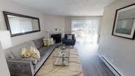 Located at 5700 23rd St E in Fife, Washington, this single-floor residence offers a thoughtfully designed layout that balances comfort and functionality. The living room serves as the heart of the home, centered around a classic white-mantled fireplace with a tiled surround. Large sliding glass doors with vertical blinds flood the space with natural light and provide direct views of the surrounding greenery and outdoor area. Durable wood-style flooring runs throughout, complementing the neutral-toned walls and textured ceiling. The kitchen features crisp white shaker cabinetry, granite-style countertops, a soft blue-green subway tile backsplash, and stainless steel appliances including a dishwasher — offering a clean, modern aesthetic with practical storage and workspace. The bedroom is generously sized, featuring a sliding double-door closet for ample storage, a window with exterior views, and the same warm wood-style flooring found throughout the unit. Its textured ceiling and neutral palette create a calm, restful atmosphere. Overall, this residence presents a cohesive and updated interior with an inviting ambiance, practical finishes, and access to outdoor space — making it a comfortable and functional place to call home.