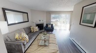 Located at 5700 23rd St E in Fife, Washington, this single-floor residence offers a thoughtfully designed layout that balances comfort and functionality. The living room serves as the heart of the home, centered around a classic white-mantled fireplace with a tiled surround. Large sliding glass doors with vertical blinds flood the space with natural light and provide direct views of the surrounding greenery and outdoor area. Durable wood-style flooring runs throughout, complementing the neutral-toned walls and textured ceiling. The kitchen features crisp white shaker cabinetry, granite-style countertops, a soft blue-green subway tile backsplash, and stainless steel appliances including a dishwasher — offering a clean, modern aesthetic with practical storage and workspace. The bedroom is generously sized, featuring a sliding double-door closet for ample storage, a window with exterior views, and the same warm wood-style flooring found throughout the unit. Its textured ceiling and neutral palette create a calm, restful atmosphere. Overall, this residence presents a cohesive and updated interior with an inviting ambiance, practical finishes, and access to outdoor space — making it a comfortable and functional place to call home.
