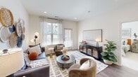 Located in Sanford, NC, this well-appointed 2-bedroom, 2-bathroom single-floor residence offers a thoughtfully designed layout with a bright, open feel throughout. The combined kitchen and living area serves as the heart of the home, with the kitchen showcasing crisp white shaker cabinetry, white subway tile backsplash, light quartz countertops, stainless steel appliances including a refrigerator, range, and microwave, and warm wood-look flooring. A kitchen island provides additional counter and seating space. The living room is generously sized with recessed lighting, large windows dressed with sheer curtains, and a glass-panel door that invites abundant natural light and outdoor views. Both bedrooms are carpeted and equipped with ceiling fans, offering a comfortable and airy retreat. The primary bedroom is a well-proportioned space with access to a full ensuite bathroom, which features a double vanity with white cabinetry, wood-look flooring, and a walk-in shower area. The secondary bathroom includes a tub-shower combination with classic white tile surround and dark fixture hardware. Two dedicated closets with wire shelving systems provide practical storage throughout the residence.