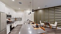 Located at Vermella in New Brunswick, NJ, this well-appointed one-bedroom, one-bathroom residence offers a thoughtfully designed open-concept layout with modern finishes throughout. Rich hardwood-style flooring flows seamlessly across the entire living space, anchoring the contemporary aesthetic.

The kitchen is a standout, featuring crisp white shaker cabinetry, a tile backsplash, grey quartz countertops, and a full suite of stainless steel appliances including a gas range, microwave, and French door refrigerator. A generous center island with a built-in sink serves as both a prep space and casual dining area, illuminated by a trio of sleek pendant lights.

The living room is distinguished by a bold, retro-patterned feature wall in earthy tones, creating a striking focal point. Sliding glass doors fill the space with natural light and provide direct access to a private outdoor patio overlooking lush landscaping.

The bedroom offers a serene retreat, complete with a textured accent wall, two built-in closets with shelving systems, and its own sliding glass doors opening to a tranquil outdoor area.

The bathroom is finished with large-format grey tile surrounding a soaking tub and shower combo, complemented by matte black fixtures for a modern touch.