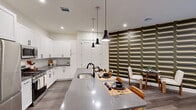 Located at Vermella in New Brunswick, NJ, this well-appointed one-bedroom, one-bathroom residence offers a thoughtfully designed open-concept layout with modern finishes throughout. Rich hardwood-style flooring flows seamlessly across the entire living space, anchoring the contemporary aesthetic.

The kitchen is a standout, featuring crisp white shaker cabinetry, a tile backsplash, grey quartz countertops, and a full suite of stainless steel appliances including a gas range, microwave, and French door refrigerator. A generous center island with a built-in sink serves as both a prep space and casual dining area, illuminated by a trio of sleek pendant lights.

The living room is distinguished by a bold, retro-patterned feature wall in earthy tones, creating a striking focal point. Sliding glass doors fill the space with natural light and provide direct access to a private outdoor patio overlooking lush landscaping.

The bedroom offers a serene retreat, complete with a textured accent wall, two built-in closets with shelving systems, and its own sliding glass doors opening to a tranquil outdoor area.

The bathroom is finished with large-format grey tile surrounding a soaking tub and shower combo, complemented by matte black fixtures for a modern touch.